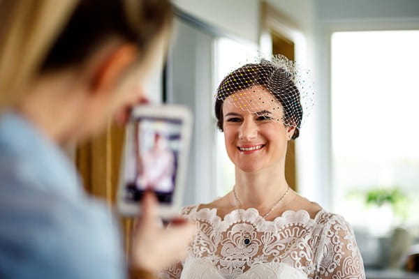 Bride smiling as friend takes picture on phone