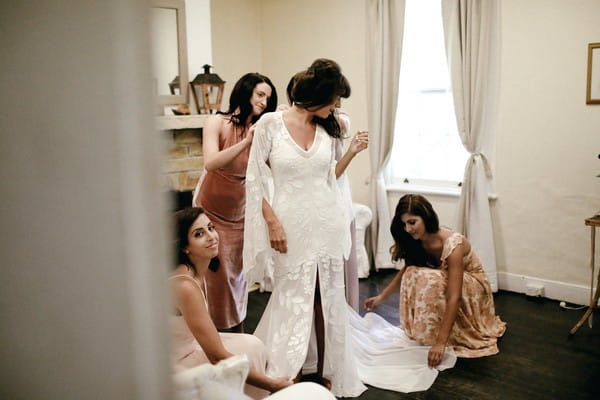 Bridesmaids helping bride get dressed