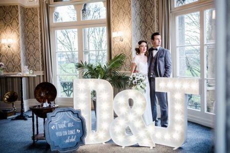 1920s bride and groom behind light up letters at The Duke of Cornwall Hotel