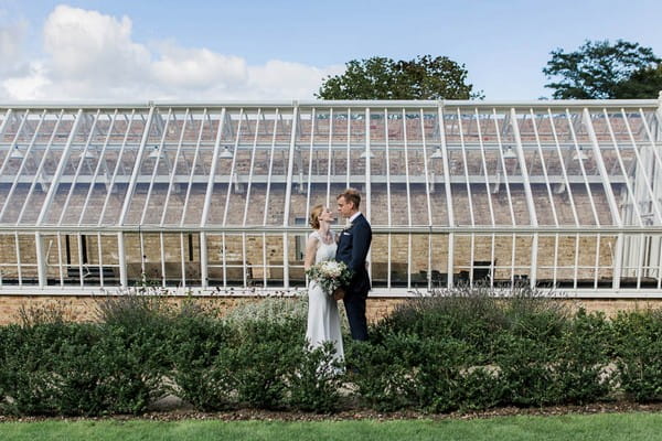 Bride and groom in front of greenhouse at Langtons House