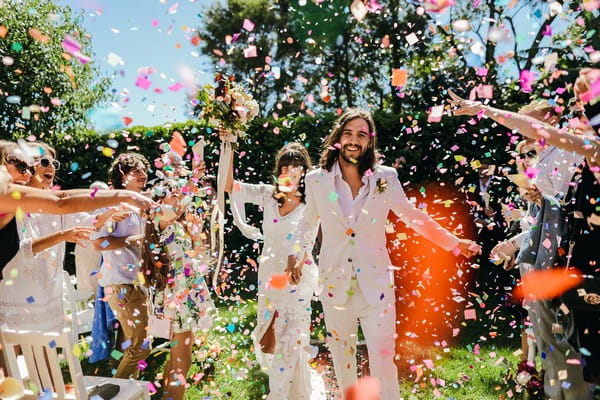 Bride and groom walking through a colourful shower of confetti