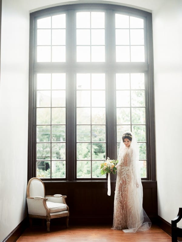 Bride standing by large windows