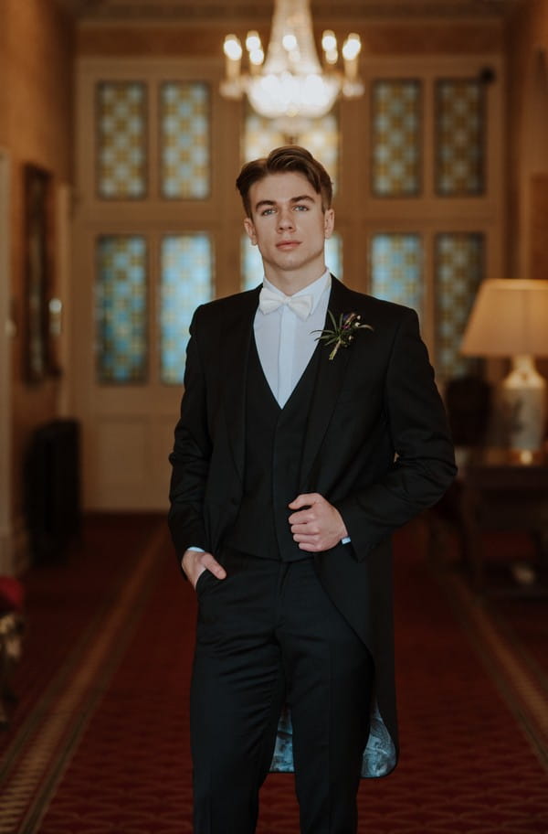 Groom wearing smart suit and white tow tie