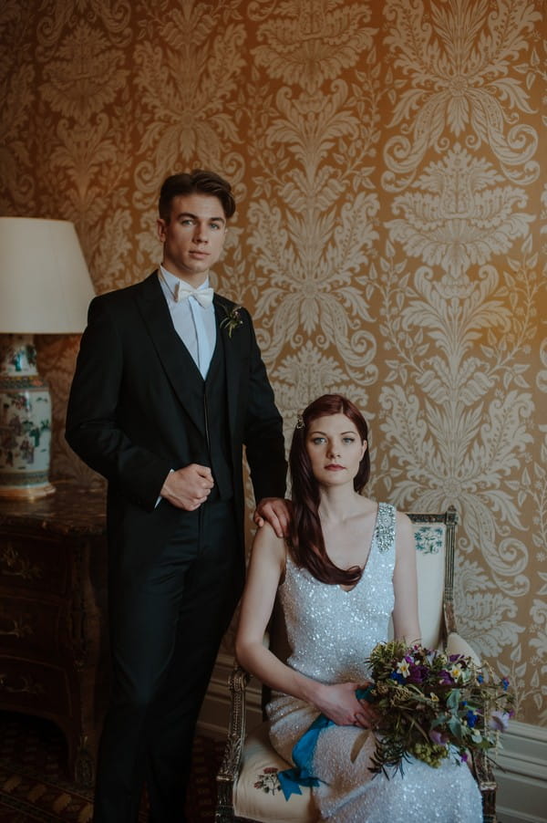 Groom standing next to bride sitting in chair