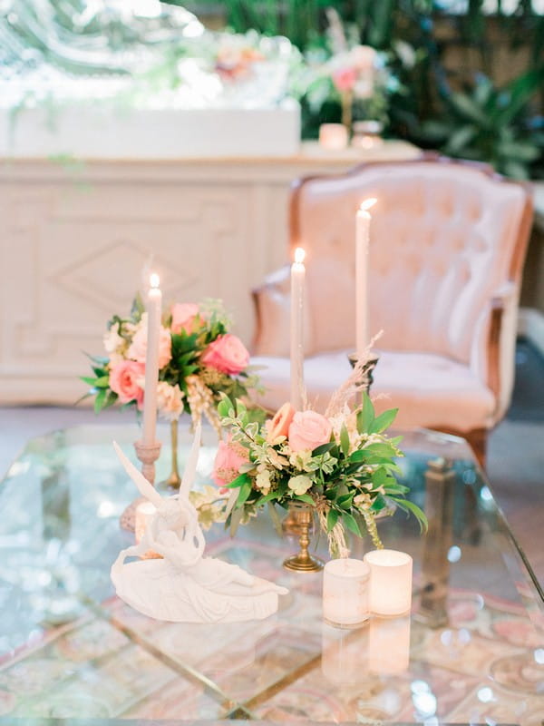 Candles and peach wedding flowers on glass table