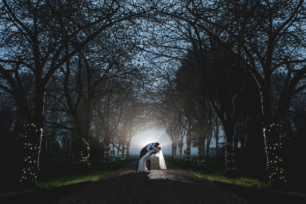 Bride and groom kissing in evening on driveway lined with trees - Picture by Daniel Ackerley Photography