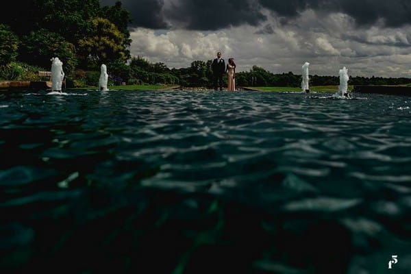 Bride and groom standing at end of water feature - Picture by F5 Photography