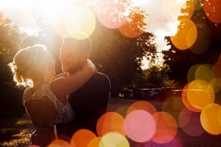 Bride and groom hugging with light spots reflecting off camera lens - Picture by Purple Pear Tree Photography