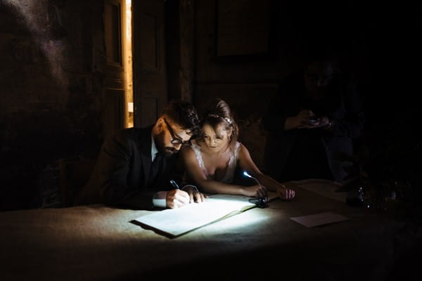 Bride watching as groom signs marriage register - Picture by Nick Tucker Photography