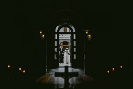 Bride and groom entering darkly lit chapel - Picture by Rares Ion