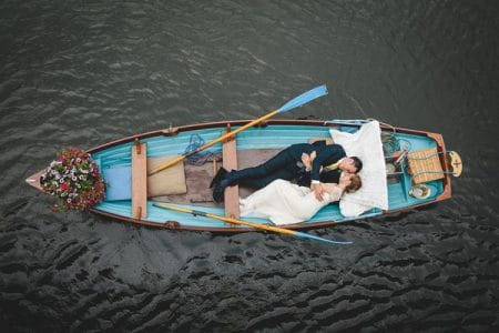 Bride and groom laying down in rowing boat - Picture by Mark Leonard Photography