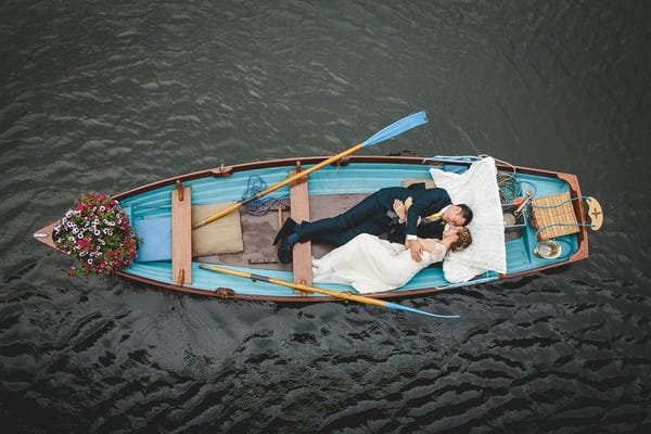 Bride and groom laying down in rowing boat - Picture by Mark Leonard Photography