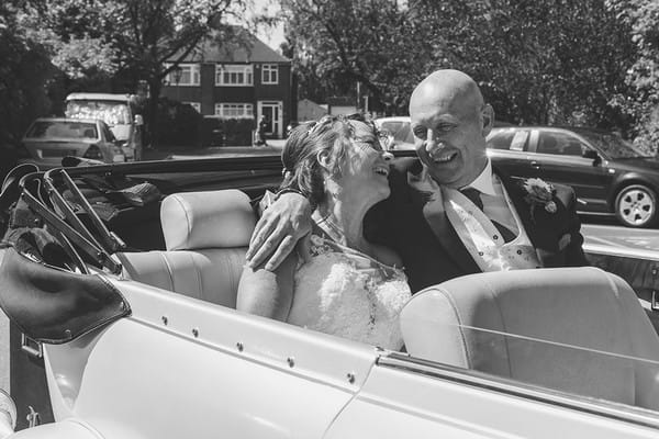 Happy bride and groom sitting in back of convertible wedding car - Picture by Life Through A Lens - Rachel Ellis Photography