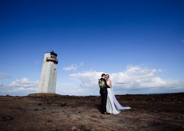 Bride and groom on Southerness beach with lighthouse in background - Picture by Giles Atkinson Photography