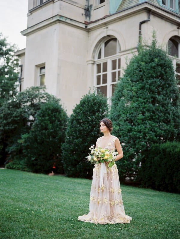 Bride holding bouquet on lawn