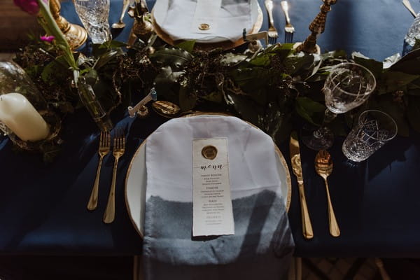 Wedding place setting with dark blue and gold styling