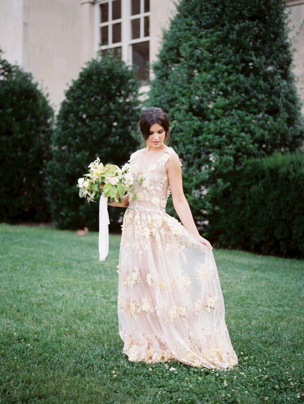 Bride holding out dress on lawn