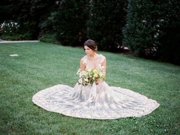 Bride sat on lawn with dress pulled out around her