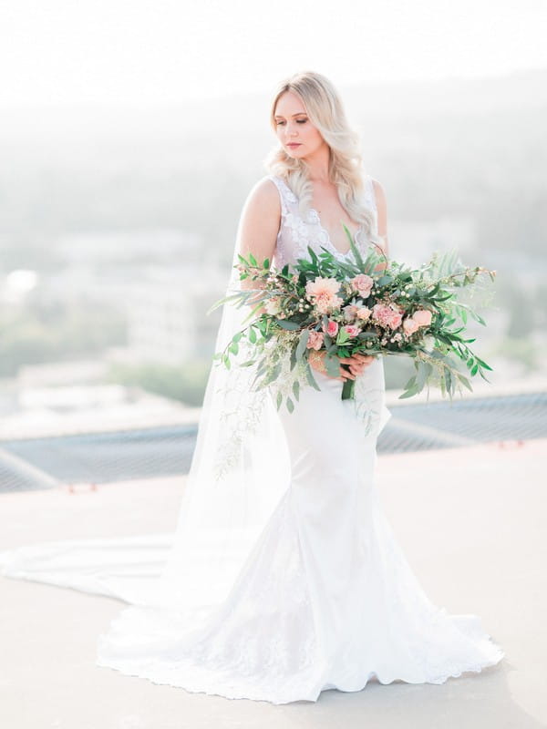 Bride holding bridal bouquet of foliage and peach flowers