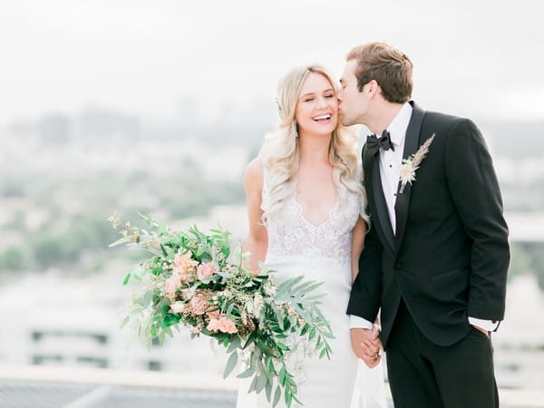 Groom kissing bride on cheek