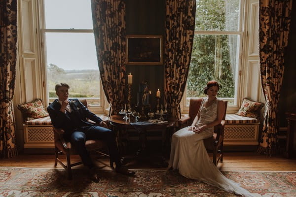 Bride and groom sitting next to cake table at Kilworth House