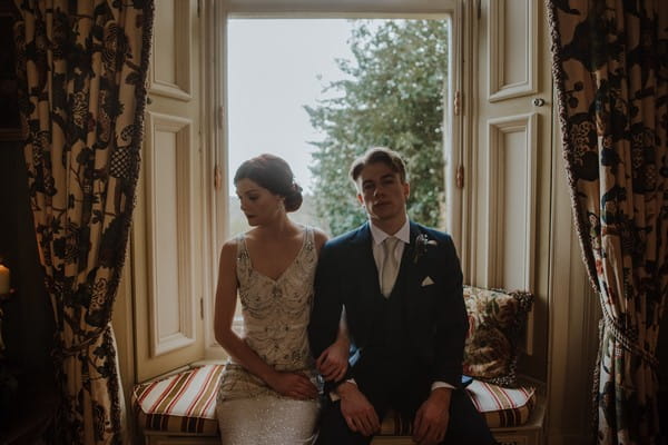 Bride and groom sitting in front of window at Kilworth House