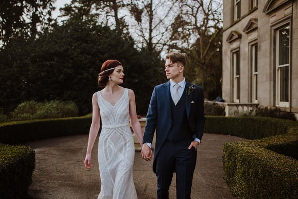 Bride and groom walking holding hands outside Kilworth House