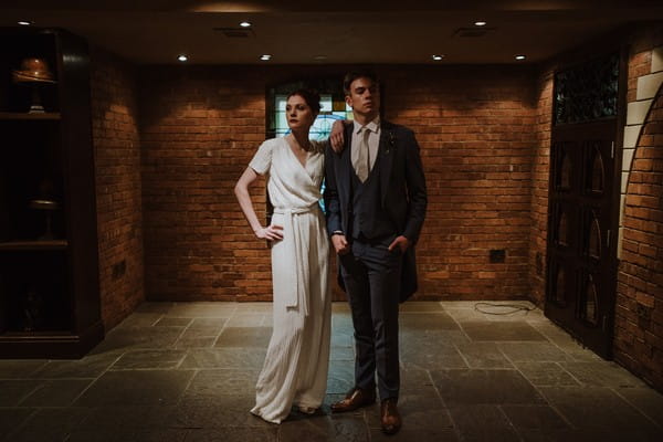 Bride leaning on groom's shoulder as he stands with hands in pockets