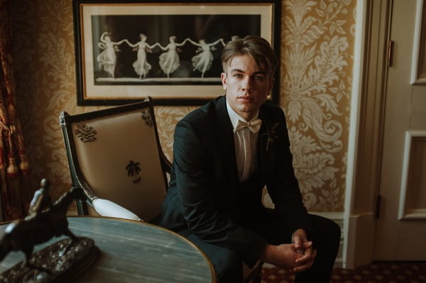 Groom with white bow tie sitting in chair