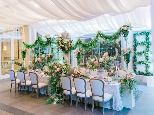 Wedding table display covered in flowers and foliage with statue centrepiece