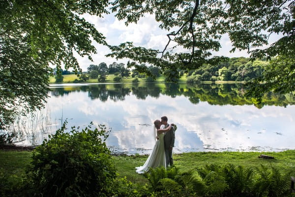 Bride and groom by lake at Combermere Abbey