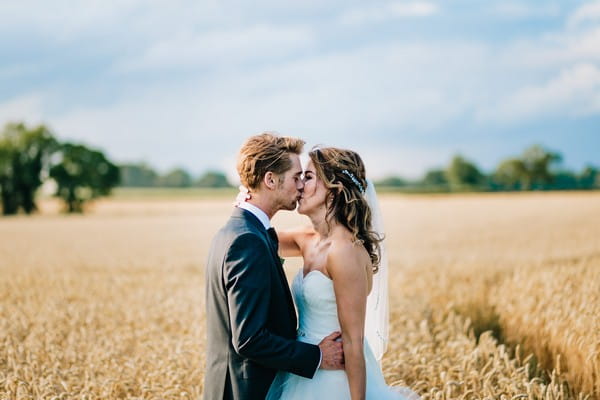 Bride and groom kissing in cornfield