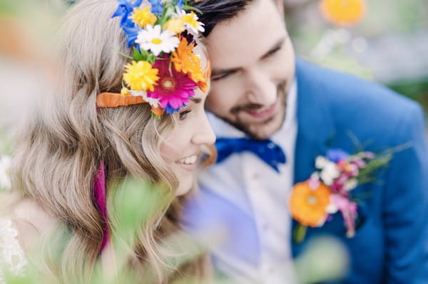 Bride with colourful floral headband resting head on groom