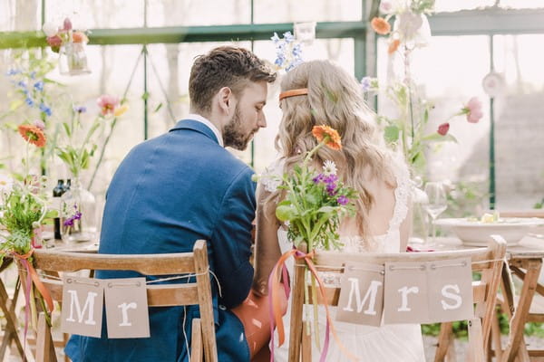 Bride and groom sitting on Mr and Mrs chairs