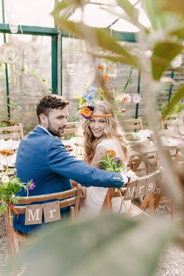 Bride and groom sitting at wedding table looking over their shoulders