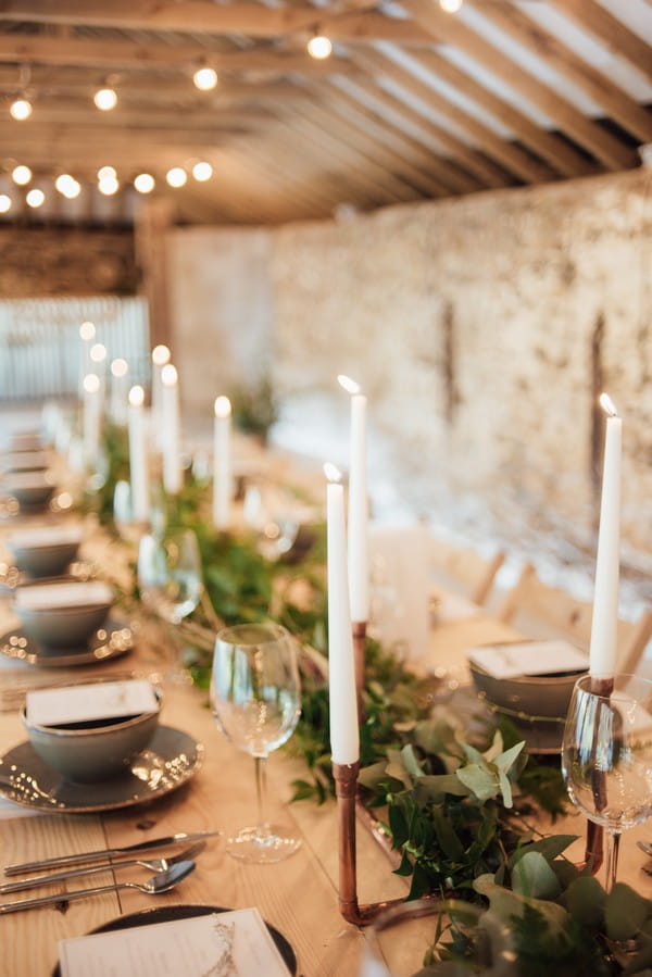 Candles and foliage lining centre of wedding table