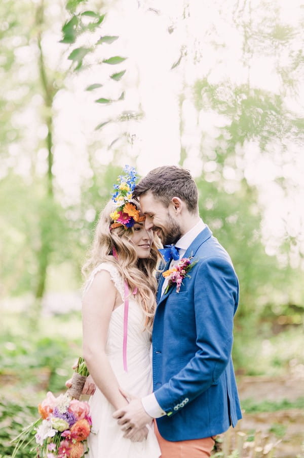 Groom in blue jacket with boho bride with colourful floral headband