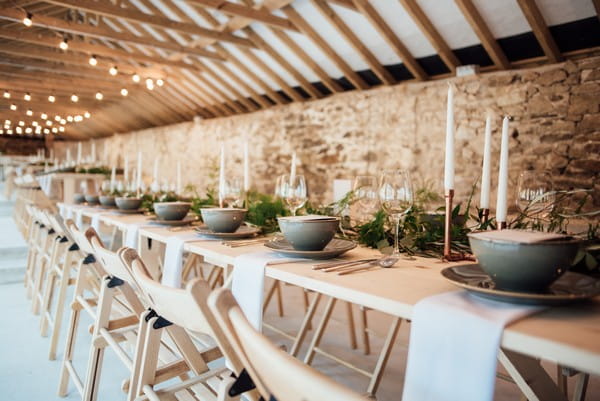 Long rustic wedding tables in The Cowyard Barn at Pengenna Manor