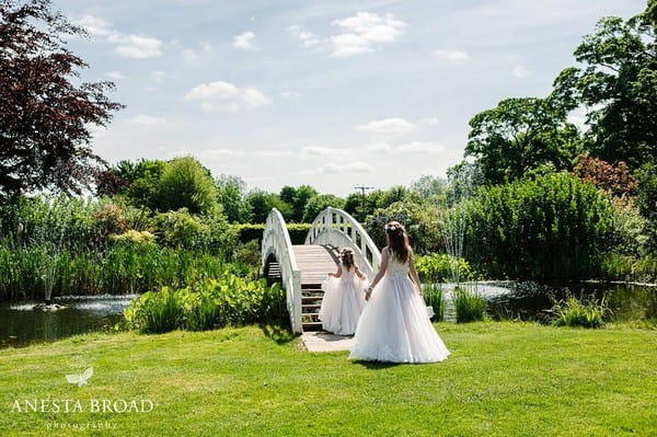 Two young bridesmaids about to walk over bridge over water - Picture by Anesta Broad Photography