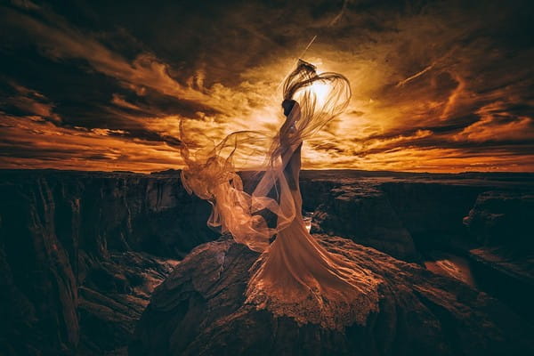 Dramatic picture of bride standing on rocks with sun shining through cloudy sky - Picture by Emin Kuliyev