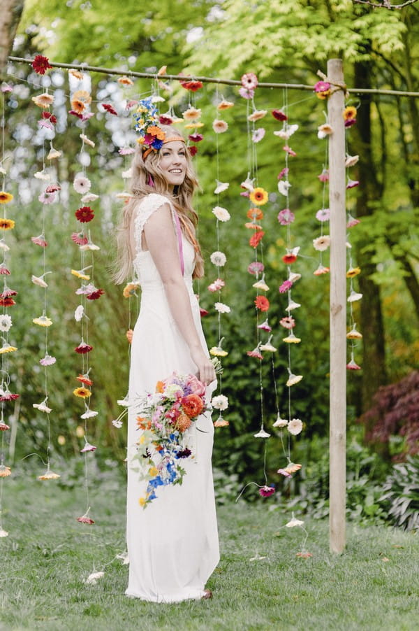 Boho bride in front of colourful suspended floral backdrop