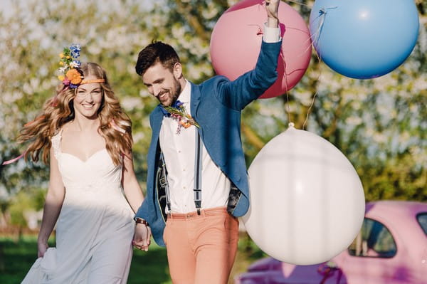 Bride with groom holding colourful balloons