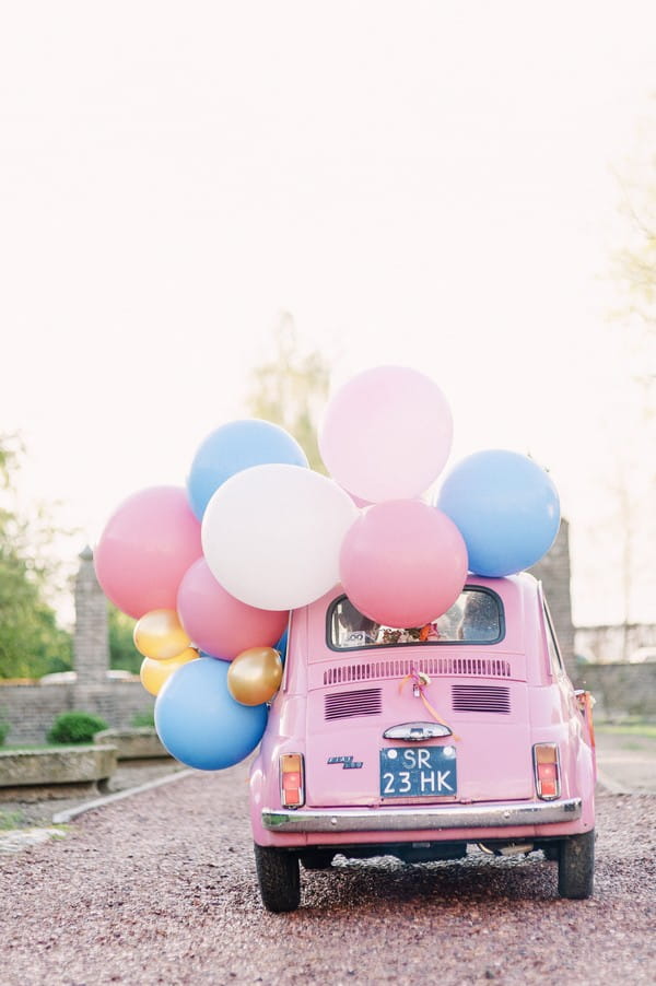 Pink car with colourful balloons tied to it