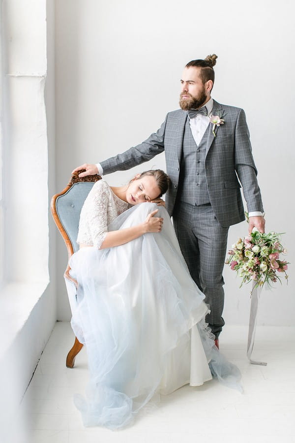 Groom standing next to bride sitting in chair
