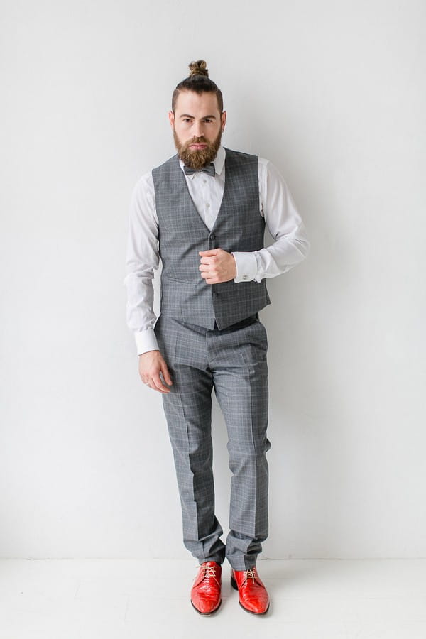 Groom wearing grey check waistcoat and bow tie with red shoes