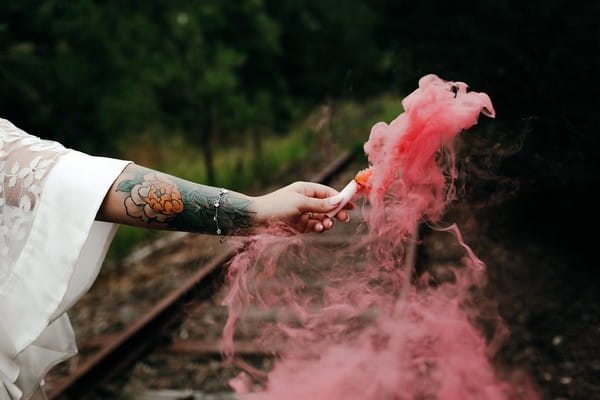 Bride holding out pink smoke bomb