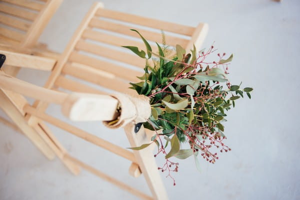 Hand tied bouquet attached to wooden wedding chair