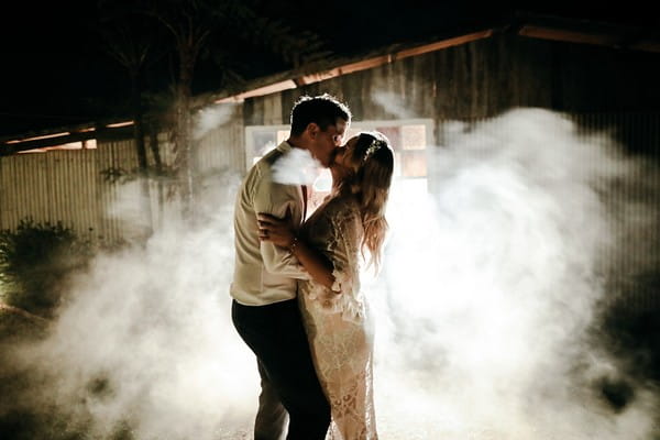 Bride and groom kissing surrounded by smoke