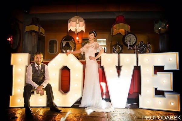 Bride and groom in front of large illuminated LOVE letters