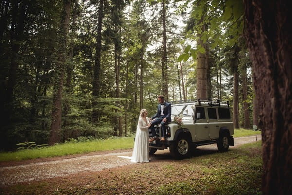 Bride with groom sitting on bonnet of Jeep - Picture by Bethany Lloyd-Clarke Photography